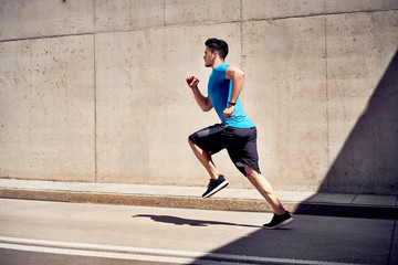 Fototapeta na wymiar City workout concept. Athletic man doing running exercises on unused road