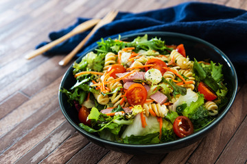 Salad with fusilli pasta accompanied tomatoes, mozzarella, smoked ham and italian cheese