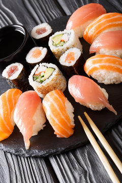 Served a set of sushi with salmon and tuna, California rolls, maki, soy sauce closeup on the table. vertical