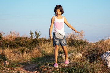 The girl walking in the field on warm and sunny summer day