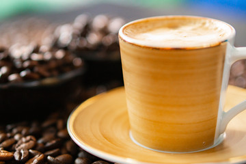 Stylish cup of coffee standing on coffee beans and beans in a stylish dish