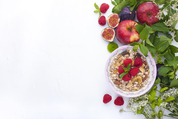 Delicious and healthy breakfast on a white background. Porridge of oatmeal, raspberry, honey, bananas, figs, mint fresh for a good morning. Free space for text, top view