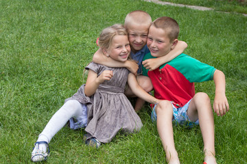Obraz premium happy kids on the grass,children hugging themselves laughing while sitting on the grass