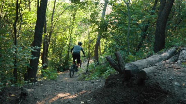 mountain biker rushes along road in forest, slow motion