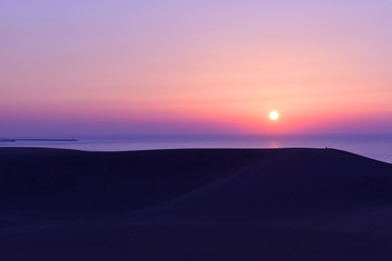 Fototapeta na wymiar 夕陽が沈む鳥取砂丘の夕景