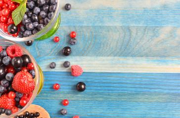 Berries of blue black and red on blue wooden background healthy food