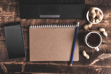Flat lay. Workplace. Coffee, mobile phone, peanuts and notebook. Work at home. Top view. Copy space