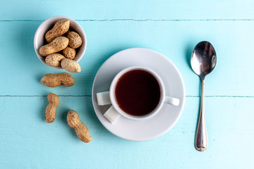 A cup of coffee and peanuts on a blue, wooden background. Awakening, morning. Top view