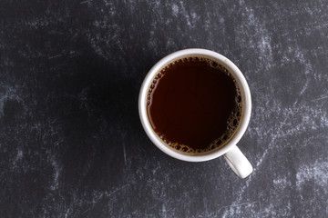 A cup of hot coffee on a dark background. Top view. Copy space