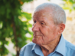 Very old man portrait. Grandfather relaxing outdoor at summer. Portrait: aged, elderly, senior. Close-up of old man sitting alone