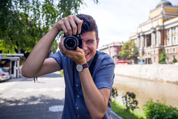 Close up view of young man with digital camera outdoors.Photographer photographing outdoor