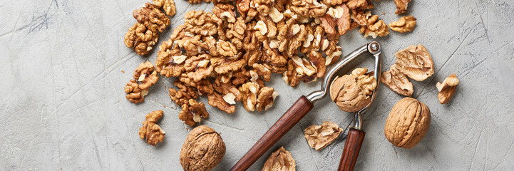 Walnut kernels on gray background and nutcracker.