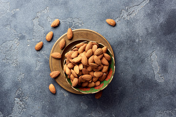 Almond nuts in bowl on gray concrete background wit copy space. Top view.