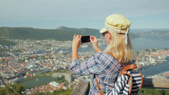 Young Woman takes a picture of the city of Bergen. She stands on the viewing platform