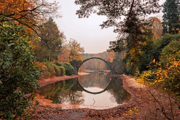 Rakotzbrücke (Rakotzbrucke, Teufelsbrücke) in Kromlau, Sachsen, Deutschland. Bunter Herbst, Spiegelung der Brücke im Wasser bilden einen geschlossenen Kreis. Ungewöhnliche und interessante Orte in Deutschland.