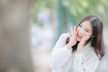 portrait of asian girl with white shirt smile and shouting in outdoor nature vintage film style