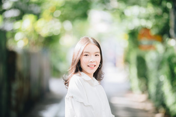 portrait of asian girl with white shirt and skirt looking smile in outdoor nature vintage film style