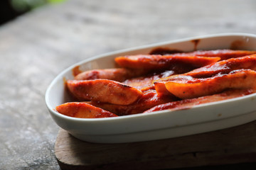 Traditional German currywurst pieces of sausage with curry sauce on wood background