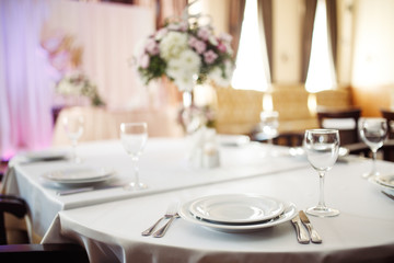 Sparkling glassware stands on long table prepared for wedding dinner.