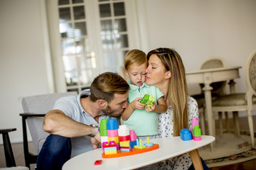 Naklejka premium Little boy playing toys with mother and father at home