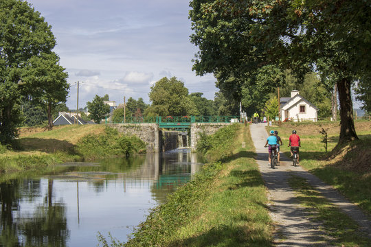Cyclistes sur le canal de Nantes à Brest, écluse n° 116 de Poulhibet à Guerlédan, Morbihan, France