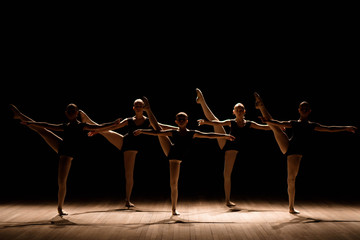 A choreographed dance of a group of graceful pretty young ballerinas practicing on stage in a classical ballet school
