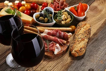 Fototapeten Italienische Antipasti-Wein-Snacks. Käsesorte, mediterrane Oliven, Crudo, Prosciutto di Parma, Salami und Wein in Gläsern über Holzschmutzhintergrund. © beats_