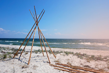 Foundation for Indian wigwam lodge or teepee made of pine wood at the seashore at summer. travel concept. copyspace