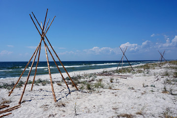 Foundations for Indian wigwams lodge or teepees made of pine wood at the seashore at summer. travel concept. copyspace © MichaelPervak