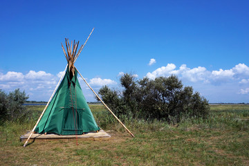 Indian wigwam lodge or teepee between trees and plants. travel concept. copyspace