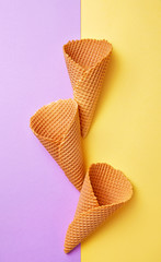 Three empty ice cream cones on a double colored backgrounds viewed from above. Waffle ice cream...