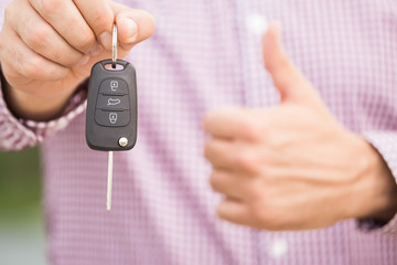 Man holding car key with thumbs up. Car dealership and rental concepts.