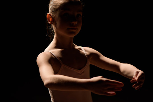 Very young ballerina posing on a black background