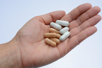 Mano mostrando un cóctel de diferentes medicamentos para el tratamiento de enfermedades como el VIH o simplemente como complementos alimenticios o adelgazamiento