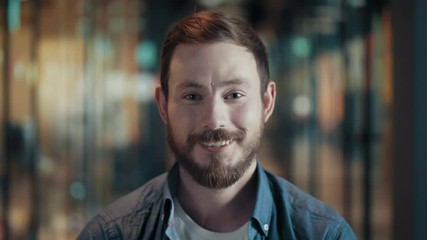 Portrait of creative young male with beard and mustache close up face of european cheerful guy in modern big start up office casual man in good positive mood looks and smiles