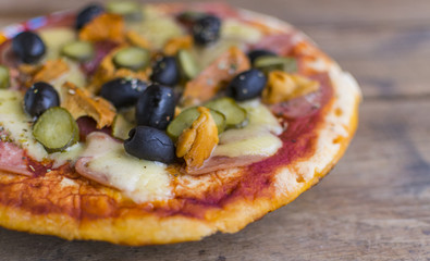 Homemade pizza with tomato sauce, cheese , olives , ham and mushrooms on wooden table