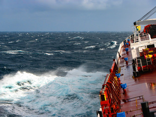 The storm in the ocean, in sunny weather, the tanker banked on the wave.