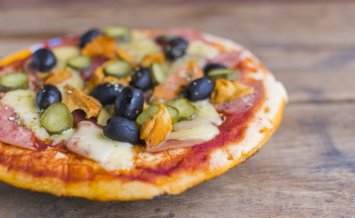 Homemade pizza with tomato sauce, cheese , olives , ham and mushrooms on wooden table