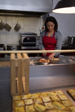 Female baker cutting dough while preparing for pasta