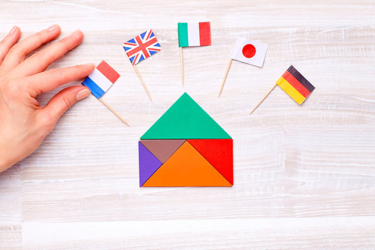 A colored house, assembled from geometric figures, with flags of different countries on wooden background