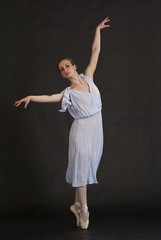 Young ballerina in blue dress isolated on black. Dance school.