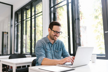 Fototapeta premium Portrait of happy young freelancer using laptop.