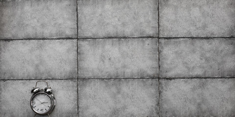 silver alarm clock on a gray cement wall