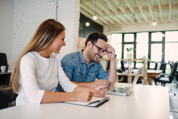 Smiling business colleagues working in modern open space office.