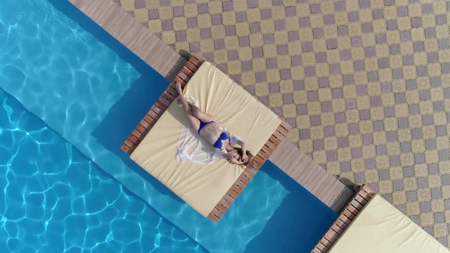 summertime, flying a drone over sexy girl lies on a terrace near a pool with blue beautiful water