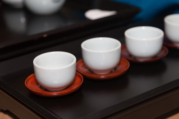 Close-up of White Tea Cups Lined up on red wooden saucers