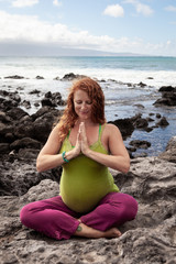 Fototapeta na wymiar Pregnant Young Woman Meditating Along the Shore in Hawaii