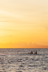 Fototapeta premium Silhouette of Two People Paddling in a Boat During Sunset.