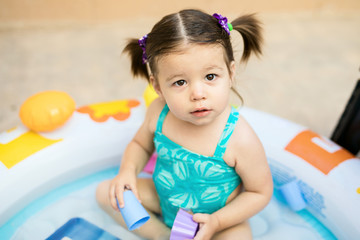 Toddler with ponytails in an inflatable pool