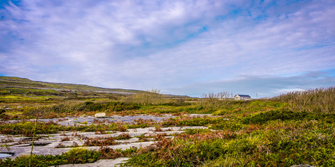 View of the scenery of Inis Mor in Ireland, showing the fields, dry stone walls and traditional farm houses. Taken on an overcast day.